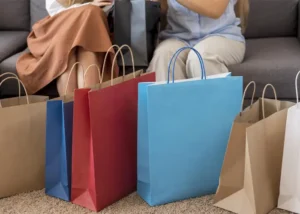 Two women sitting down next to their new purchases, discussing how to stop impulse buying and save more.