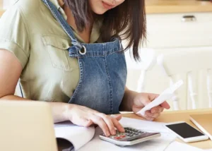 A woman looking at her finances and thinking how to give them a good spring cleaning and purge from unnecessary expenses.